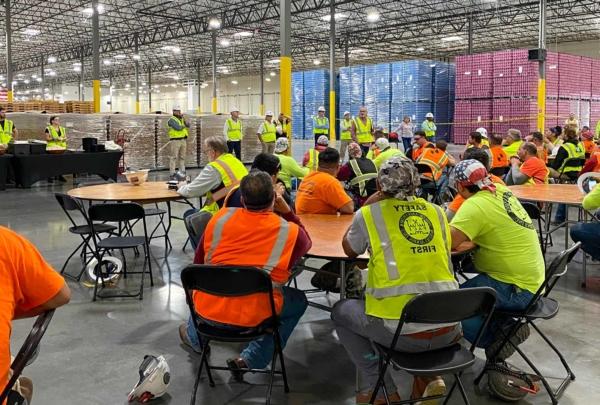 A 澳门足彩app 建设 crew gathers for a meeting in Bang Energy's giant warehouse